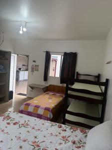 a bedroom with two beds in a room with a window at Recanto dos Amigos Suítes CANTÃO DO INDAIA in Bertioga