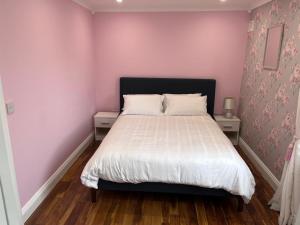 a bedroom with a bed with a pink wall at Knockeven Hidden Gem in Waterford +6 photos