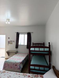 a bedroom with two bunk beds and a window at Recanto dos Amigos Suítes CANTÃO DO INDAIA in Bertioga +4 photos