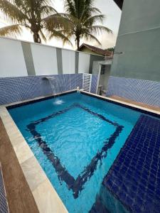 a large swimming pool with blue water in a house at Recanto dos Amigos Suítes CANTÃO DO INDAIA in Bertioga