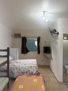a small bedroom with a bed and a window at Recanto dos Amigos Suítes CANTÃO DO INDAIA in Bertioga