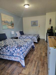 two beds in a room with wooden floors at Canton Motel in Canton
