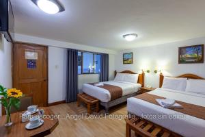 a hotel room with two beds and a table at Hotel Amerinka in Cusco