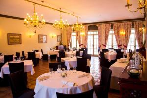 a restaurant with white tables and black chairs and chandeliers at Hotel Finca las Beatas in Villahermosa