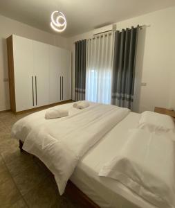 a bedroom with a large white bed and a window at Fusha Apartment in Velipojë