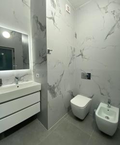 a white bathroom with a toilet and a sink at Fusha Apartment in Velipojë +7 photos