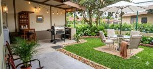 a patio with a table and an umbrella and grass at Arenal Jendrik house in Agua Azul