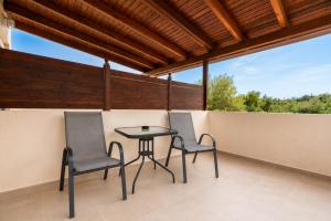 a patio with two chairs and a table on a balcony at ATH Airport Suites Free Shuttle From And To Athens Airport in Spata +23 photos