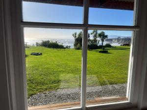 a window with a view of a field of grass at Cape Foulwind Clifftop Cabin in Cape Foulwind