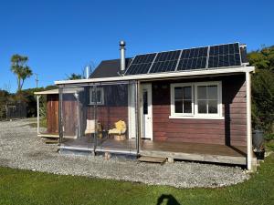 a small house with solar panels on the roof at Cape Foulwind Clifftop Cabin in Cape Foulwind