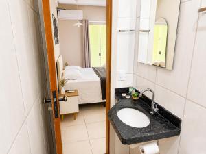 a bathroom with a sink and a bedroom at Isa Flats in Janaúba +14 photos
