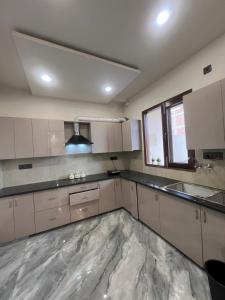 a kitchen with white cabinets and a large marble floor at Aura Villa in Ghaziabad