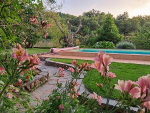 a swimming pool in a garden with pink flowers at Monte do Rei Santo in Arronches
