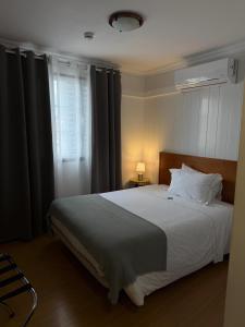 a bedroom with a large white bed and a window at Hospedaria Insular in Ponta Delgada