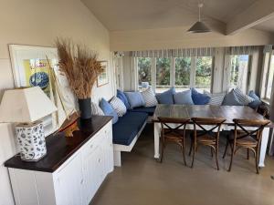 a living room with a couch and a table and chairs at The Bach - beachfront in Waimarama