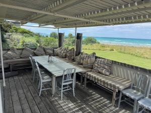 a patio with a couch and a table and chairs at The Bach - beachfront in Waimarama