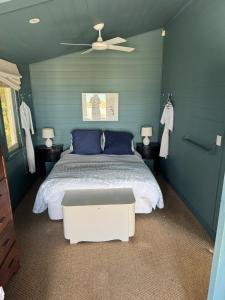 a bedroom with a bed with blue walls and a ceiling at The Bach - beachfront in Waimarama