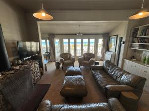 a living room with a leather couch and chairs at The Bach - beachfront in Waimarama