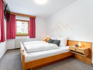 a bedroom with a bed with white sheets and a window at An der Ache XL in Kirchberg in Tirol