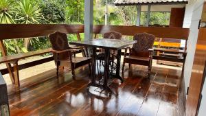 a wooden table and chairs on a porch at ริมแควโฮมสเตย์ กาญจนบุรี in Ban Pong Pat