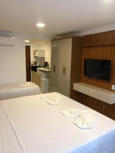 a bedroom with two beds and a flat screen tv at Ponta Negra Flat 305 in Natal