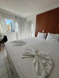 a bedroom with a white bed with a bow on it at Ponta Negra Flat 305 in Natal +8 photos