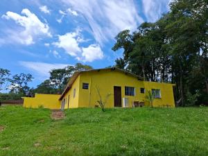 a yellow house on a grassy field with a sky at Chácara Solar de Jarinu in Jarinu