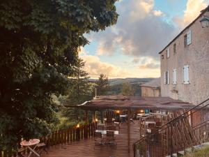 a deck with chairs and umbrellas next to a building at La Bastide en Margeride in Châteauneuf-de-Randon