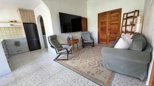 a living room with a couch and chairs and a television at Villa Alam in Nusa Lembongan