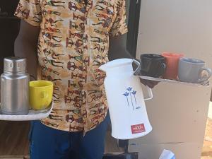a person holding a tray with a pitcher and cups at The Brookshore in Kodaikānāl