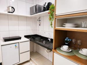 a small kitchen with white appliances and a sink at Isa Flats in Janaúba