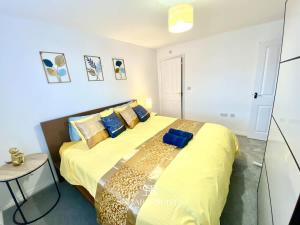 a bedroom with a large bed with yellow sheets and blue pillows at 4 Bed House with Driveway Parking for 2 Cars - Rugby - Sleeps 10! Perfect for groups! in Rugby
