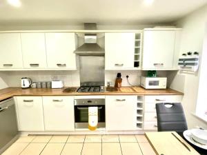 a kitchen with white cabinets and a stove top oven at 4 Bed House with Driveway Parking for 2 Cars - Rugby - Sleeps 10! Perfect for groups! in Rugby