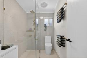 a bathroom with a toilet and a glass shower at Boutique Bribie Stay in Bellara +22 photos