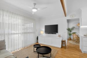 a living room with a tv on a white cabinet at Boutique Bribie Stay in Bellara