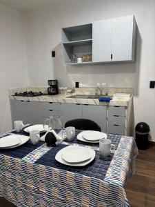 a table with plates and dishes on it with a kitchen at Demi Apartment in Zaachila +11 photos
