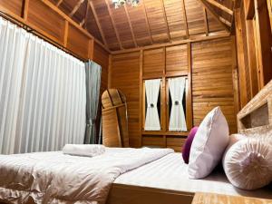 a bedroom with a bed in a wooden room at Pondok Nisya in Sawan