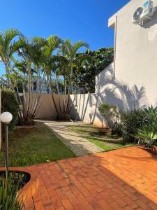 a house with palm trees and a brick walkway at Sobrado Savana in Foz do Iguaçu