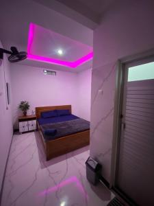 a bedroom with a bed with a purple lighting at Penginapan Angsoka 1 in Singaraja