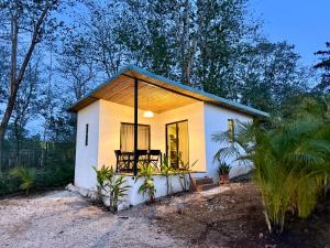a small white house with a chair on the porch at Avellanas Tiny Villa 1BR Private Self check in in Santa Cruz