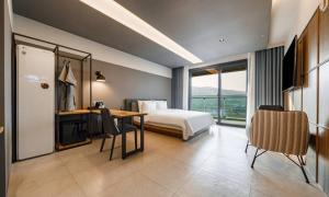 a hotel room with a bed and a desk and a table at Anseong Nomad Hotel in Anseong