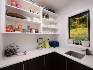 a kitchen with white shelves and a sink and a window at Moana View in Paihia +48 photos