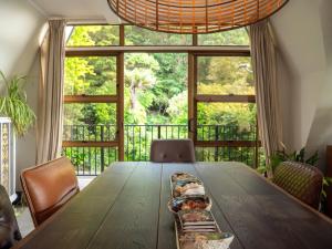 a dining room with a wooden table and a large window at Moana View in Paihia