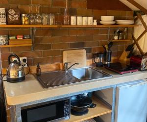 a kitchen counter with a sink and a microwave at Nikau Sanctuary in Raglan +11 photos