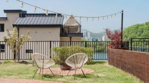 two white chairs sitting in the grass near a fence at Chuncheon Rehouse in Chuncheon