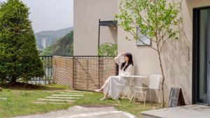 a woman sitting at a table in front of a building at Chuncheon Rehouse in Chuncheon +5 photos