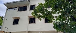 a white building with black windows and a tree at Melinda place in Camarin
