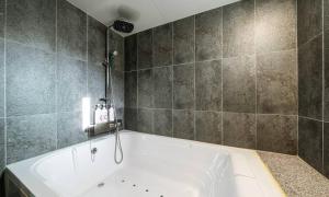 a bath tub in a bathroom with tiled walls at Anyang ILLOWA Hotel in Anyang +38 photos
