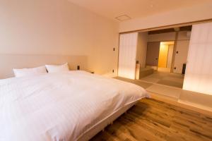 a bedroom with a white bed and a large mirror at SATOYAMA STAY Nino-Machi in Furukawachō