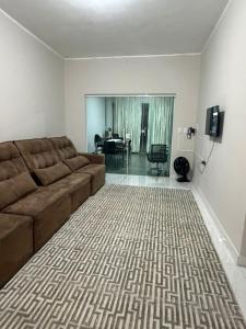 a living room with a brown couch and a dining room at casa da piscina e churrasco in Maringá